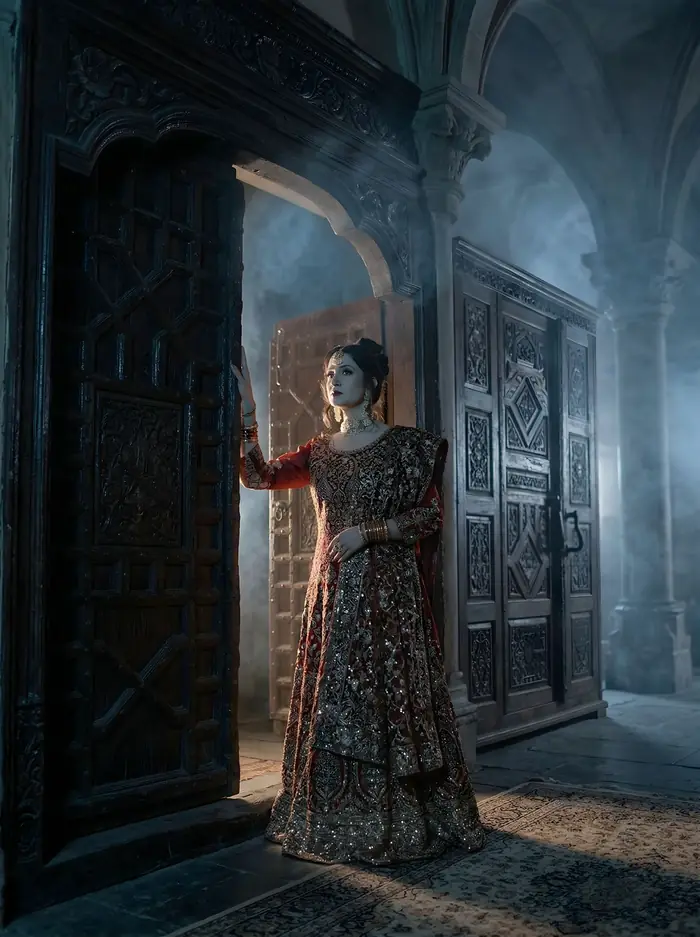 Malaika Faisal in a red bridal lehenga in a mist-filled stone archway