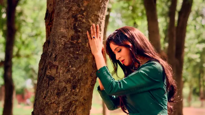 Close portrait of Malaika Faisal leaning against a tree trunk, eyes closed